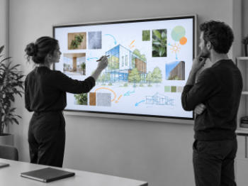 Zwei Personen arbeiten an einem interaktiven Display mit Architekturentwurf, Referenzbildern und handschriftlichen Anmerkungen.
